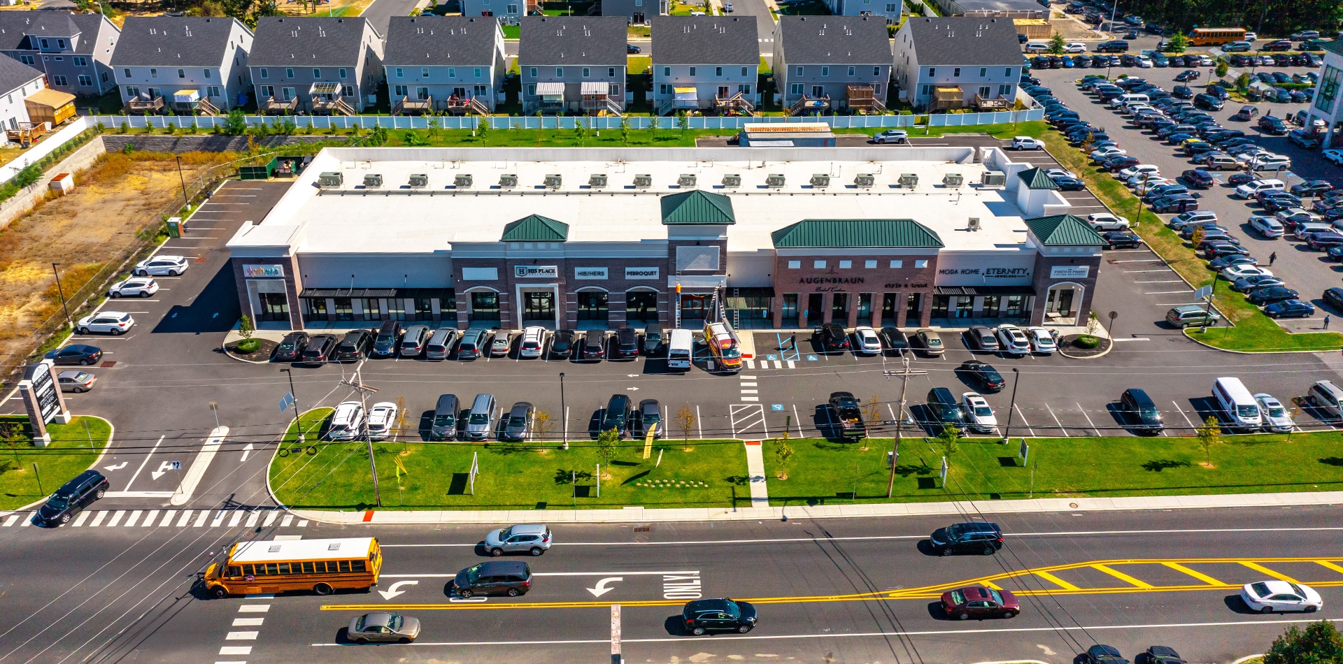 Ariel image of a housing community, multiple parking lots, and a busy street with traffic.