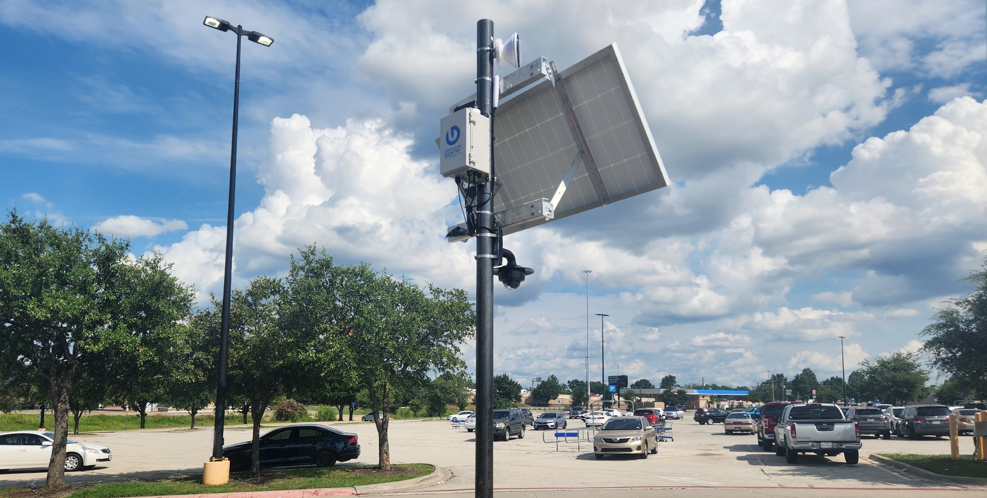 A Gridless Sentry unit, multi-sensor security camera, and solar panel mounted on a pole oversee a big box retail store parking lot.